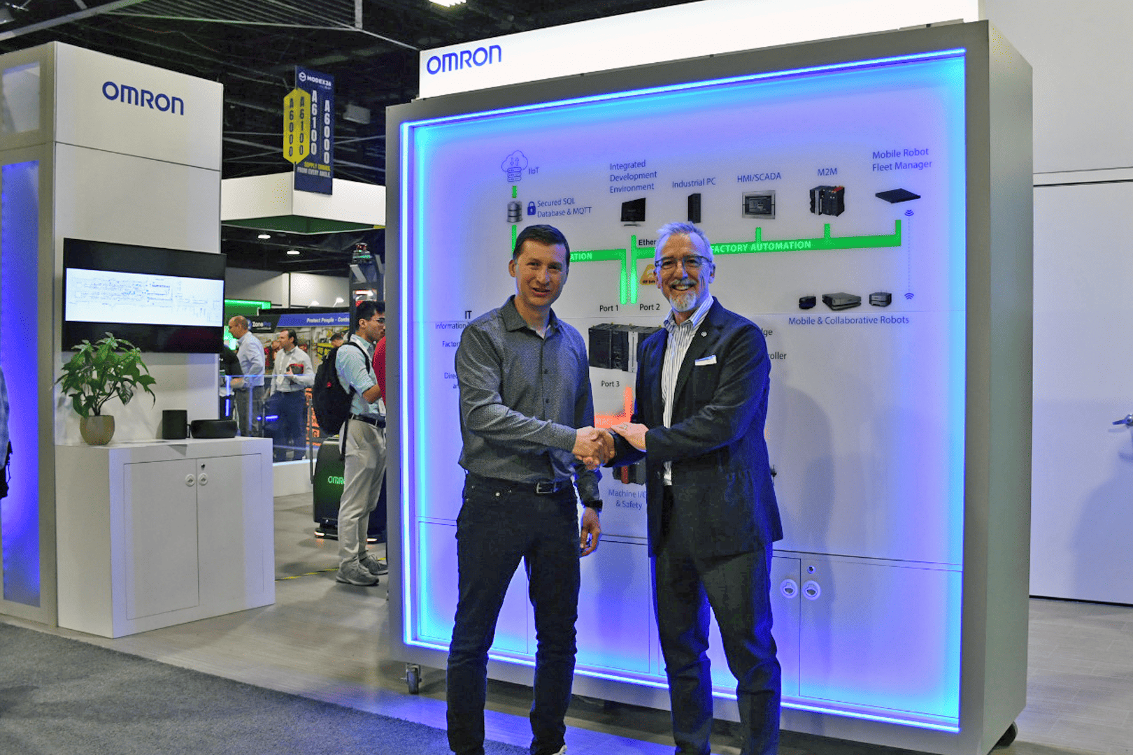 OMRON Robotics and Comau representatives at an industrial automation exhibition stand