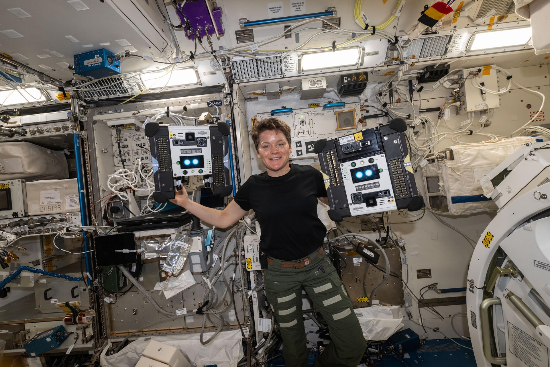 NASA astronaut Anne McClain with two Astrobee free-flying robots inside the International Space Station’s Kibo module