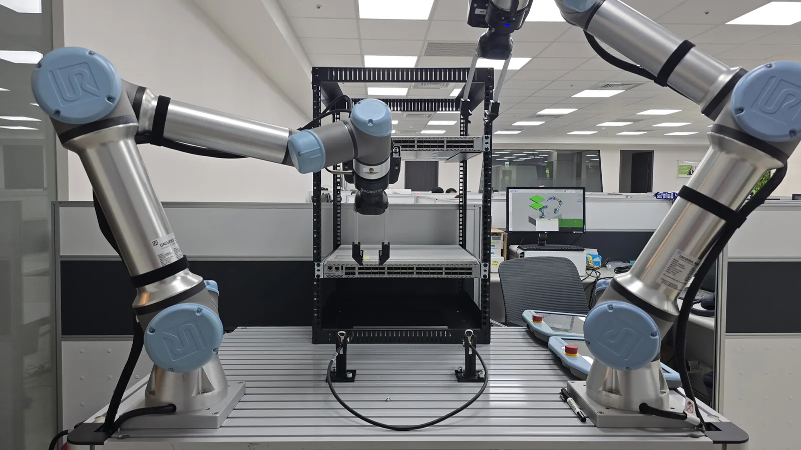 Two Universal Robots cobots working around a server-rack cable-insertion demonstration